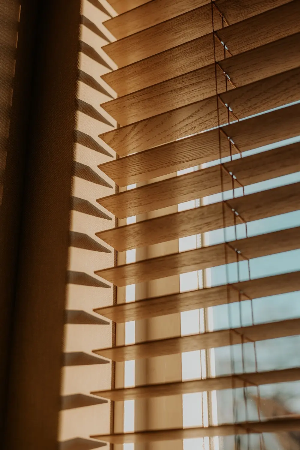 Napfény szűrődik át a fa lamellás reluxán egy nappaliban